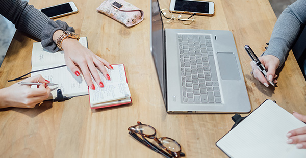 midsection two young women indoor sitting working desk
